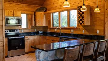 Cocina de cabaña de madera con isla central, microondas integrado, estufa y lavavajillas.