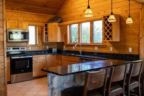 Een houten keuken in een chalet met een centraal eiland, een ingebouwde magnetron, fornuis en vaatwasser.