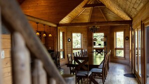 A wooden dining area with a large table and chairs, large windows, and hanging pendant lights. - Splash Mountain 6 bedrooms with indoor pool & mountain and filtered lake view (Garrett County)