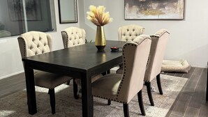 Un comedor con una mesa de madera oscura, seis sillas tapizadas, un jarrón decorativo y un ventilador de techo.