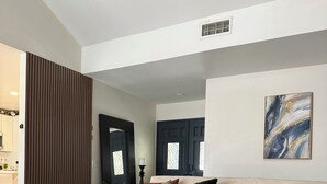 Una sala de estar moderna con un sofá color beige, una mesa de centro y un jarrón con flores.