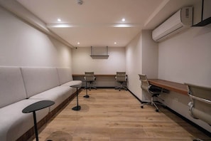 A conference room with a long table, two chairs, a sofa, and a small table. - Geko | Bright 1BR near Larcomar w/ Pool and Gym (Miraflores)