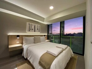 Ein modernes Schlafzimmer mit einem großen Bett, Nachttischen, einer Fensterbank und Blick auf die Stadt, inklusive Jalousien.