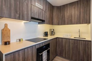 Eine moderne Küche mit Holzschränken, einem Einbauherd, einer Kaffeemaschine und einem Geschirrspüler.