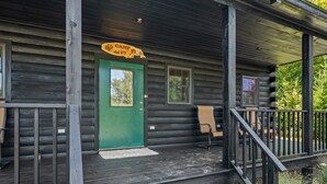 Une cabane en bois avec une porte verte, une pancarte indiquant « Camp 17 » et un banc à l’extérieur.