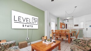 A living room with a dining area, a kitchen, and a sign that reads "LEVEL UP STAYS". - Resort stay~Pool Access~Peaceful Retreat~Balcony (Kissimmee)