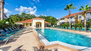 A swimming pool with lounge chairs, a covered pavilion, and a building with balconies. - Resort stay~Pool Access~Peaceful Retreat~Balcony (Kissimmee)