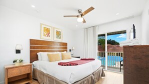 A bedroom with a bed, a nightstand, a lamp, a ceiling fan, and a view of a swimming pool. - Direct resort access~Balcony~Pool~Upgraded Inside (Kissimmee)