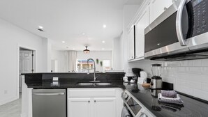 A modern kitchen with a black countertop, stainless steel appliances, and white cabinetry. - Direct resort access~Balcony~Pool~Upgraded Inside (Kissimmee)