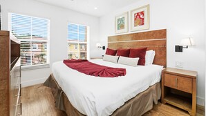 A bedroom with a large bed, a wooden headboard, two bedside tables, a ceiling fan, and two windows with blinds. - Direct resort access~Balcony~Pool~Upgraded Inside (Kissimmee)