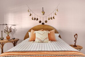 A bedroom with a wooden headboard, striped bedding, and a wall-mounted moon decoration.
