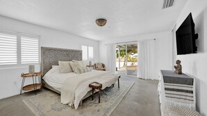 A bedroom with a bed, bedside tables, a rug, a dresser, and a window with blinds. - Casa Cosmic: Hot Tub, Fire Pit & Stargazing (Joshua Tree)