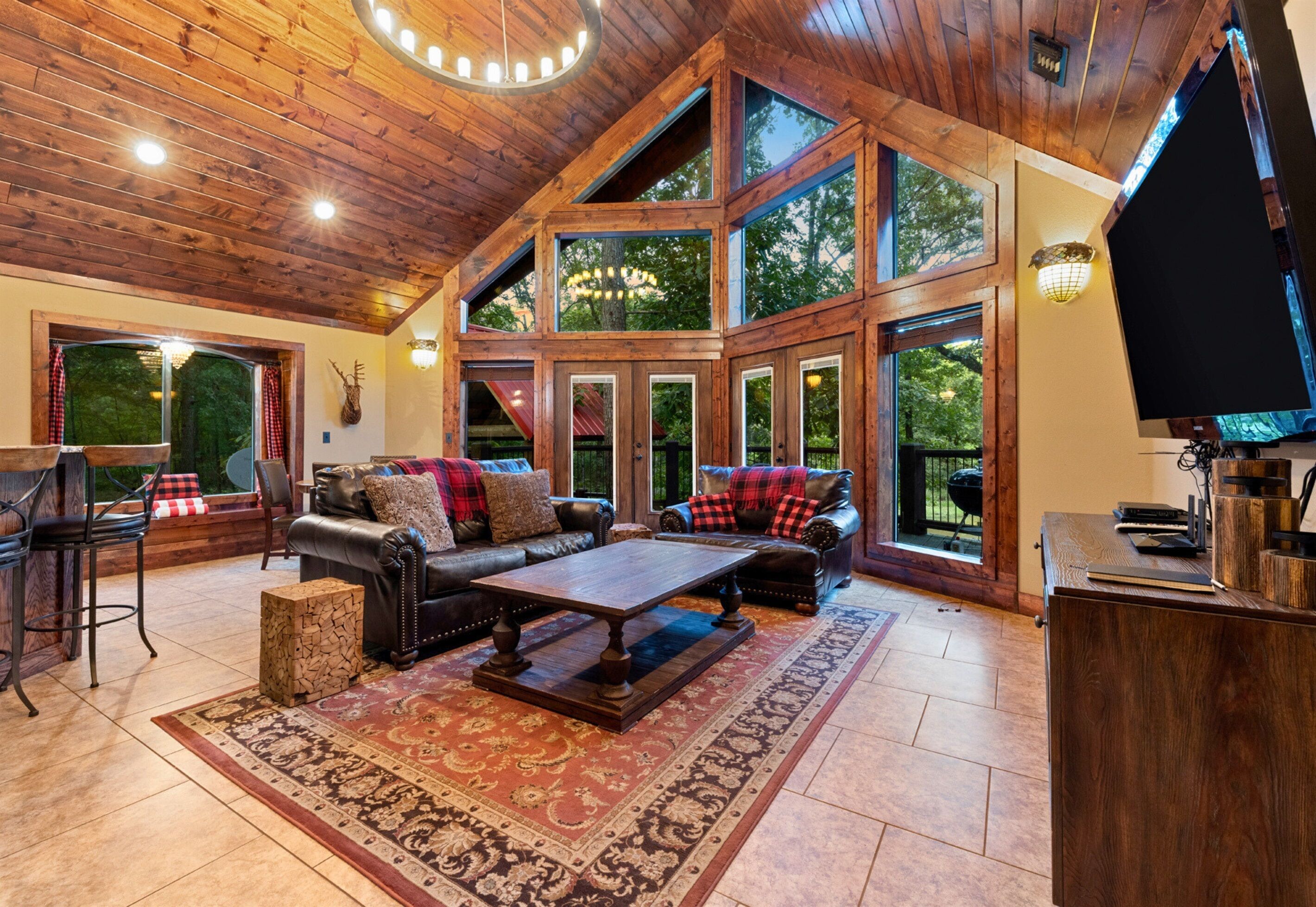 Un salón espacioso con techo alto, ventanas grandes, chimenea y televisor.