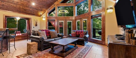 Un salón espacioso con techo alto, ventanas grandes, chimenea y televisor.