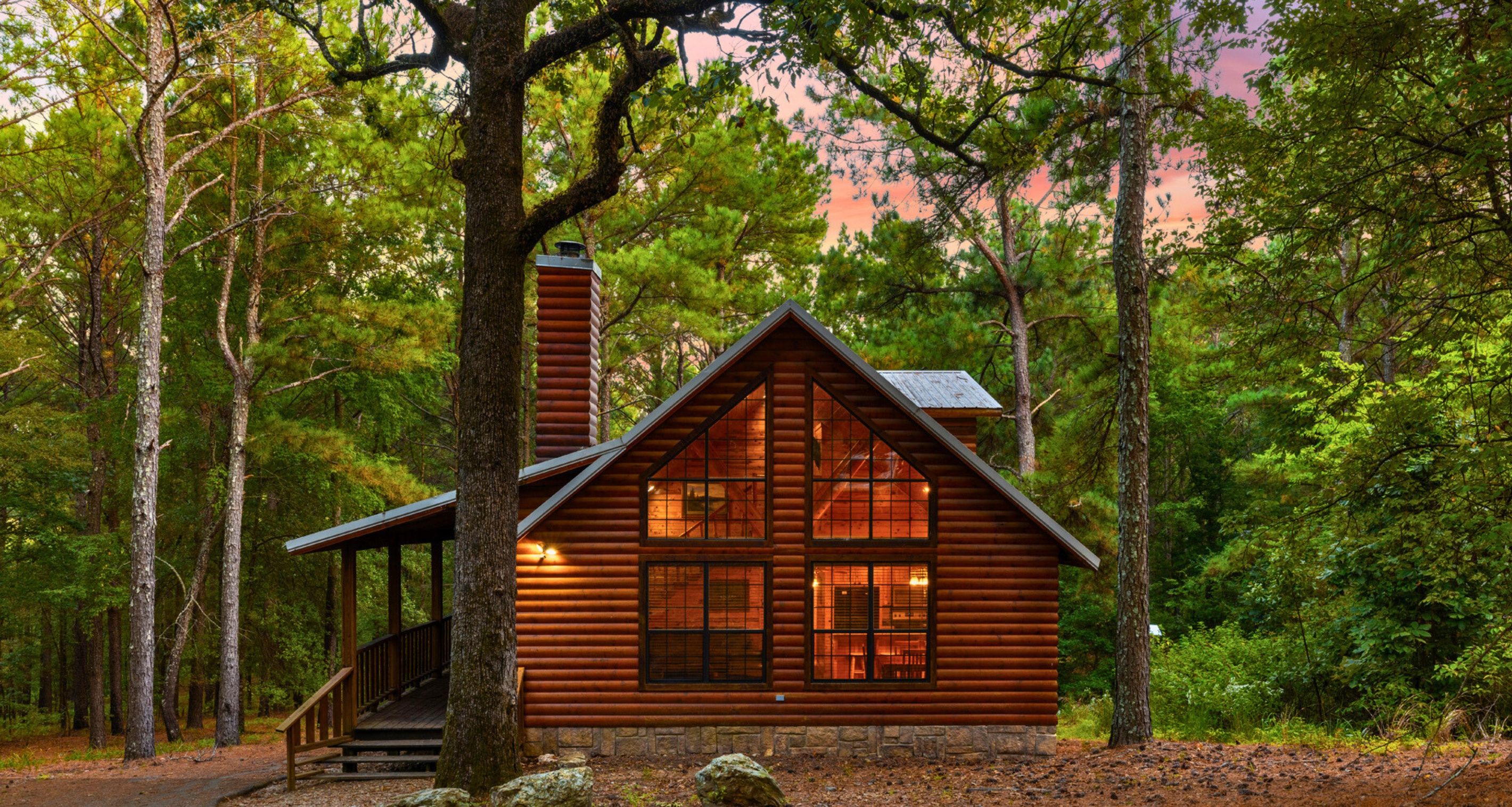 A log cabin with a chimney, a porch, and a staircase leading to the entrance.