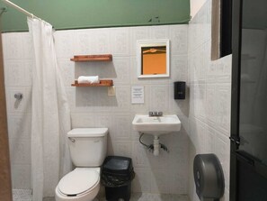 Ein kleines Badezimmer mit Toilette, Waschbecken, Mülleimer und Handtuchhalter.