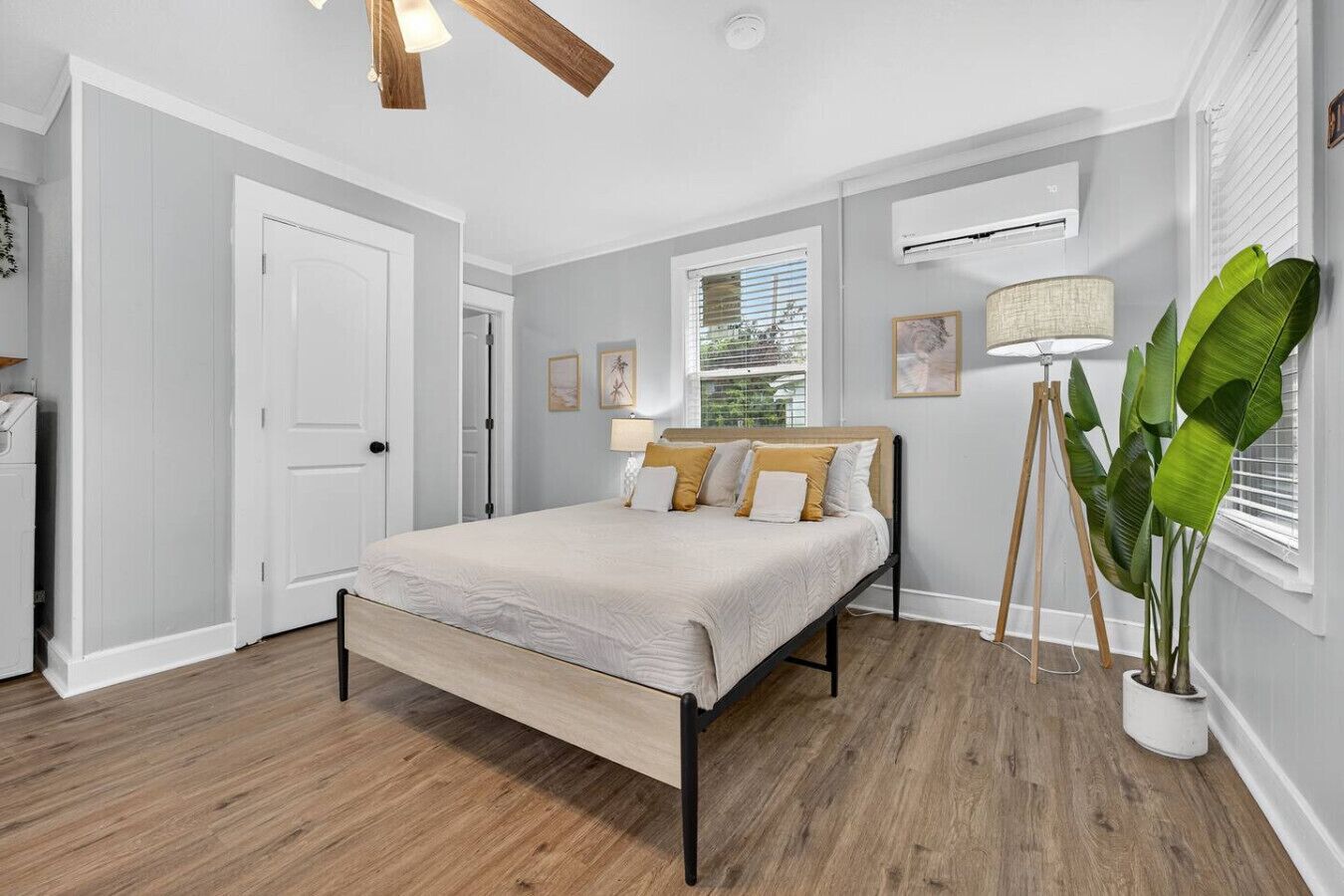 A bedroom with a bed, a standing lamp, and a potted plant.