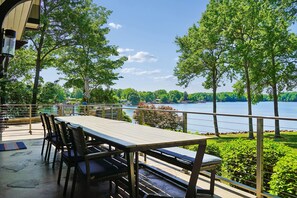 Un área de comedor al aire libre con mesa y sillas, con vista a un lago y rodeada de árboles.