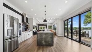 A modern kitchen with stainless steel appliances, a central island, and large windows offering a view of the outdoors.