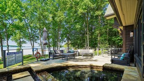 A pool area with a hot tub, lounge chairs, and a view of the lake.