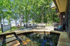 Zona de piscina con jacuzzi, sillas de descanso y vistas al lago.