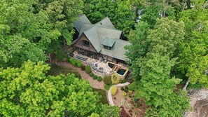 A large, two-story house surrounded by dense green trees.