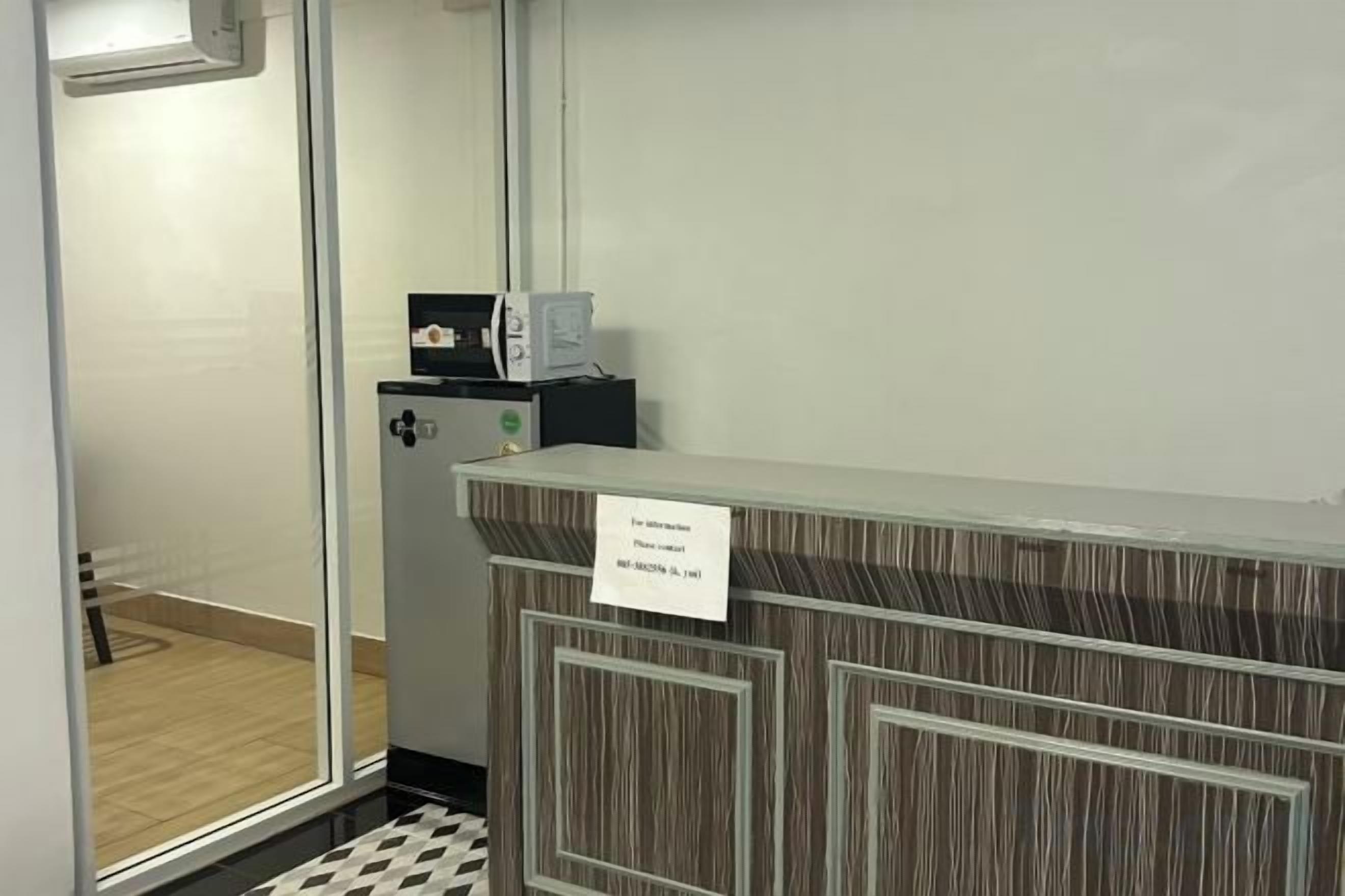 A reception desk with a sign, a glass door, and a small refrigerator.