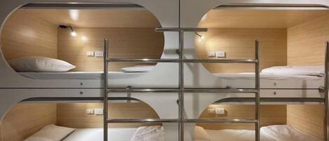 A bunk bed room with a central ladder, wooden walls, and a simple design.