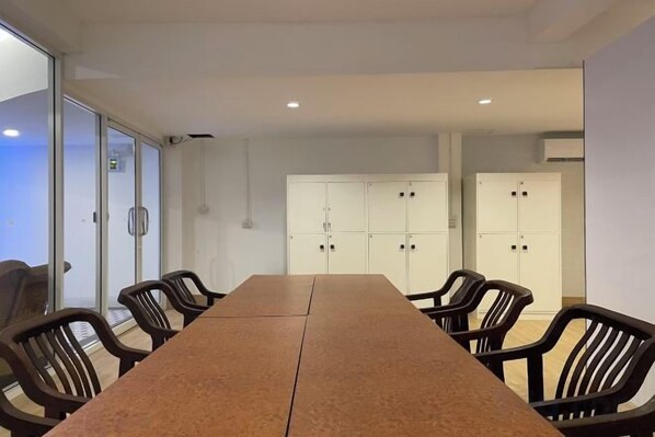 A conference room with a long table and chairs, glass walls, and cabinets in the background.