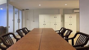 Ein Konferenzraum mit langem Tisch und Stühlen, weißen Schränken und einer Glastür.