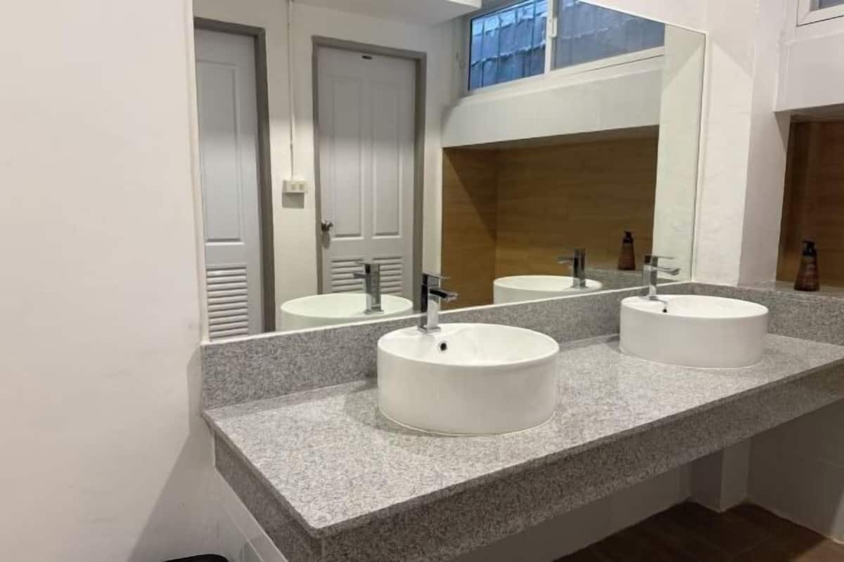 Une salle de bain avec deux vasques rondes blanches, un grand miroir et un mur d’accent en bois.