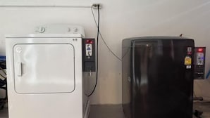 Eine weiße Waschmaschine und ein schwarzer Kühlschrank stehen nebeneinander und sind an eine Steckdose angeschlossen.