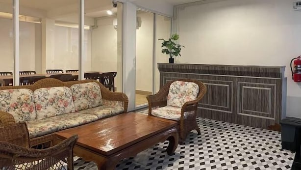 Ein Zimmer mit einer Couch, Stühlen, einem Holztisch, einem karierten Boden und einem an der Wand befestigten Feuerlöscher.