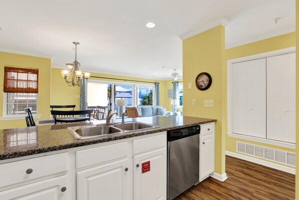 A kitchen with white cabinetry, a stainless steel sink, and a dishwasher.