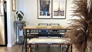 A dining area with a wooden table, bench, and framed pictures on the wall. - Bright Modern Condo Near SkyTrain & Hospital (New Westminster)