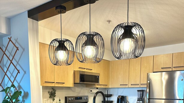 A modern kitchen with a central island, stainless steel appliances, and pendant lighting. - Bright Modern Condo Near SkyTrain & Hospital (New Westminster)