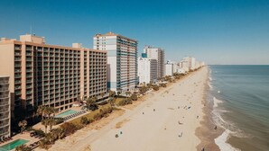 Ein Hotel an der Küste mit mehreren Etagen, einem Poolbereich und direkter Strandlage.