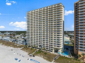 A high-rise hotel with multiple balconies, a pool, and a beach view.