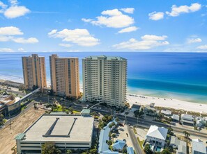 A coastal area with high-rise buildings, a beach, and a parking lot.