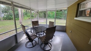 A covered patio with a table and chairs, large windows, and a view of a grassy area. - 3 Bed/2 Bath Cottage near downtown  Crystal River (Crystal River)