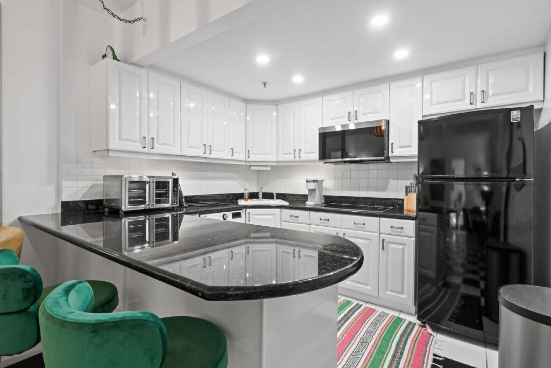 A modern kitchen with white cabinets, a black refrigerator, and a central island with seating.