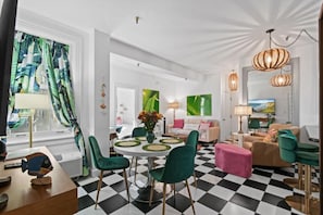 Una sala de estar moderna con piso a cuadros, sillas verdes, una mesa redonda y un sofá.