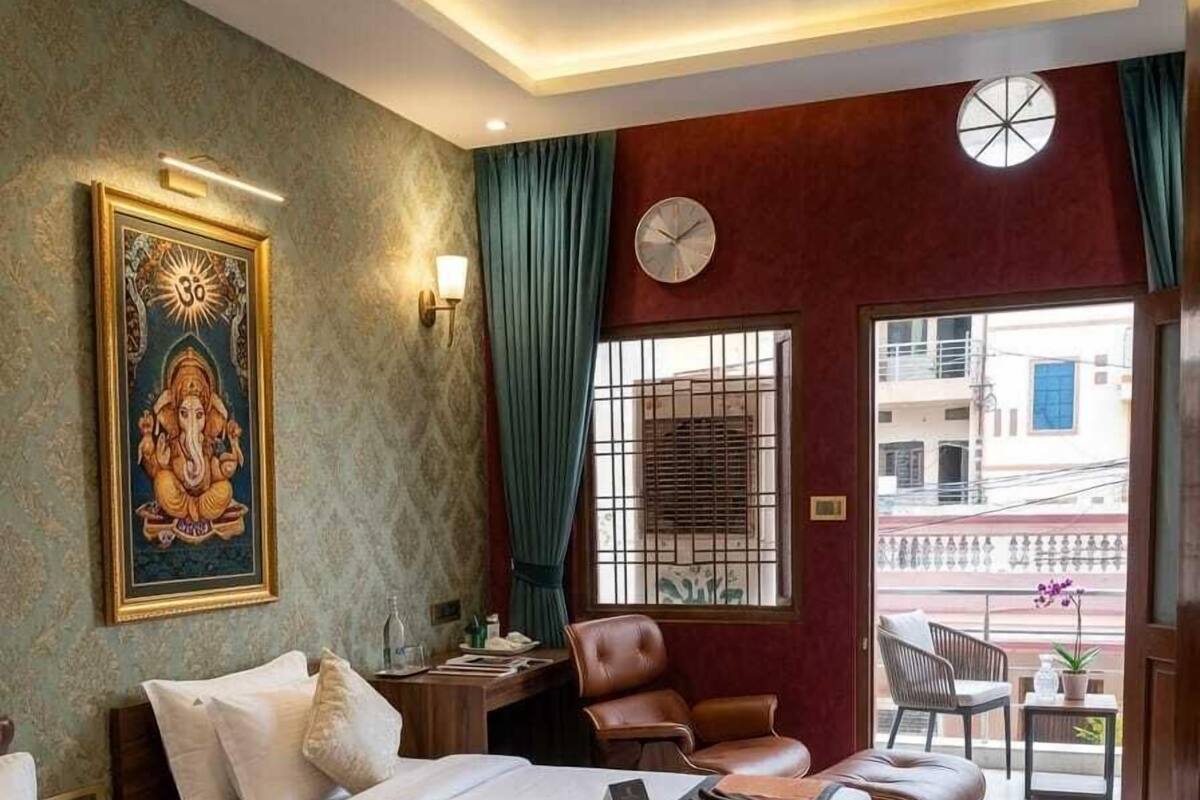 A hotel room with two beds, a desk, a chair, a clock, and a view of the outside.