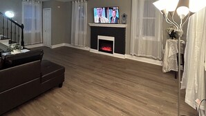Ein Wohnzimmer mit Kamin, Fernseher und Stehlampe.