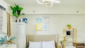 A modern hotel room with a bed, bedside tables, a desk, and a wall-mounted air conditioner. - Room-modern Studio Hideaway Near City Sp (Iloilo)