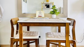 A dining table with chairs, a mirror, a clock, and a sign that reads 'Life Begins After Coffee'. - Room-modern Studio Hideaway Near City Sp (Iloilo)