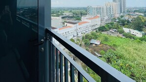 A balcony with a view of a cityscape, including buildings and greenery. - Room-modern Studio Hideaway Near City Sp (Iloilo)