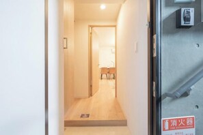 A hallway leading to a room with a fire extinguisher sign on the wall. - MAT Nogata (Tokyo)