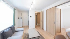 A modern, well-lit room with a sofa, a small table, and a cabinet. - MAT Nogata (Tokyo)