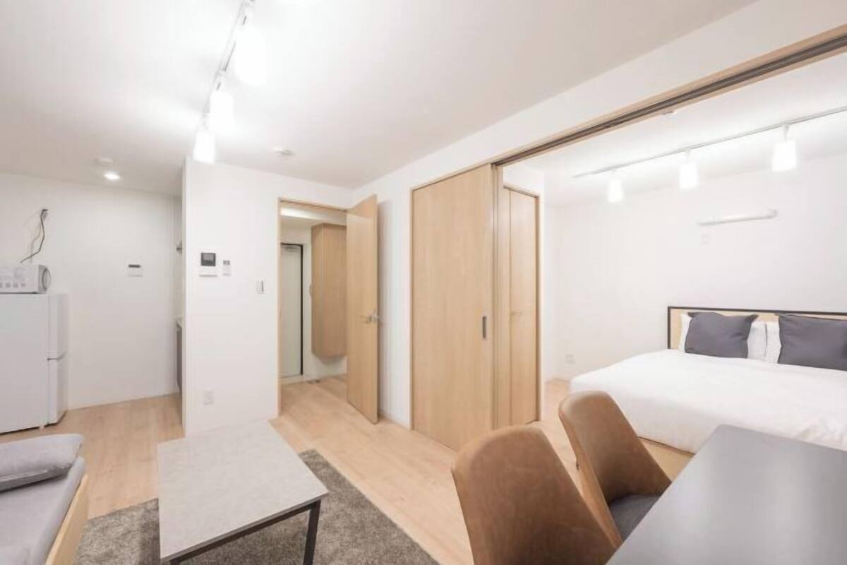 A modern hotel room with a bed, a desk, a chair, and a wardrobe.